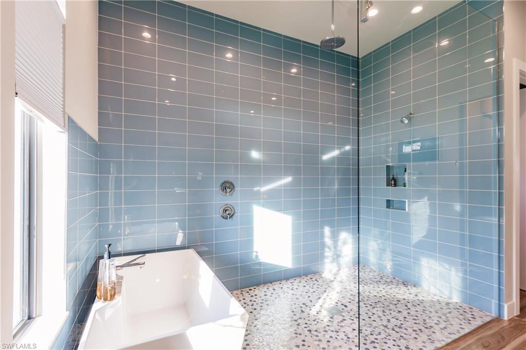 Bathroom with a freestanding bath, tiled shower, and tile walls
