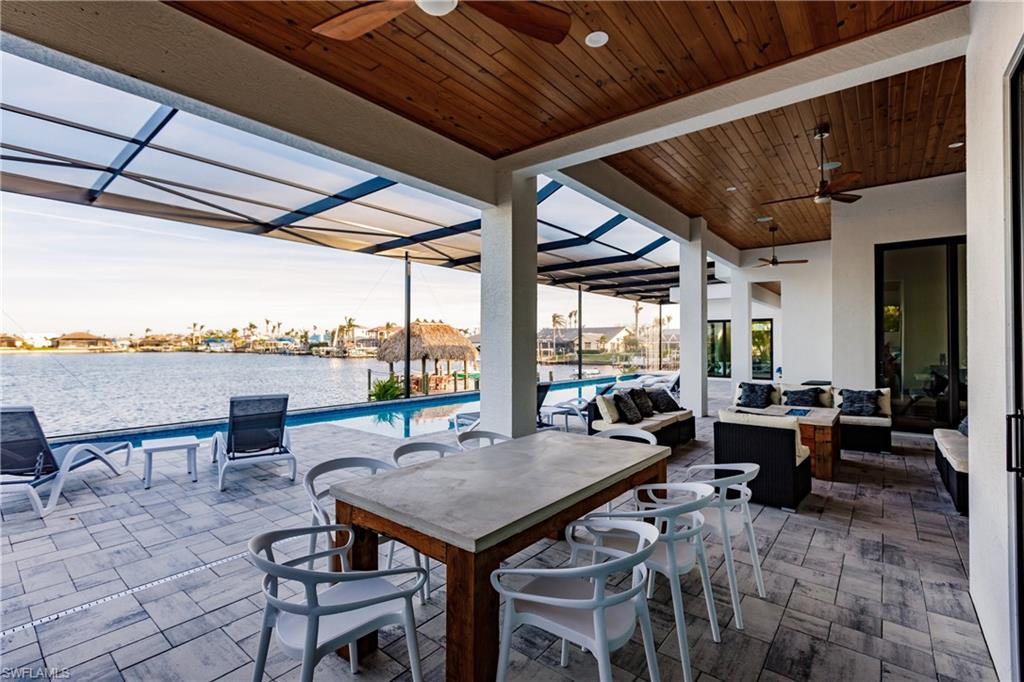 View of patio / terrace featuring a ceiling fan, a water view, outdoor lounge area, an outdoor pool, and a lanai