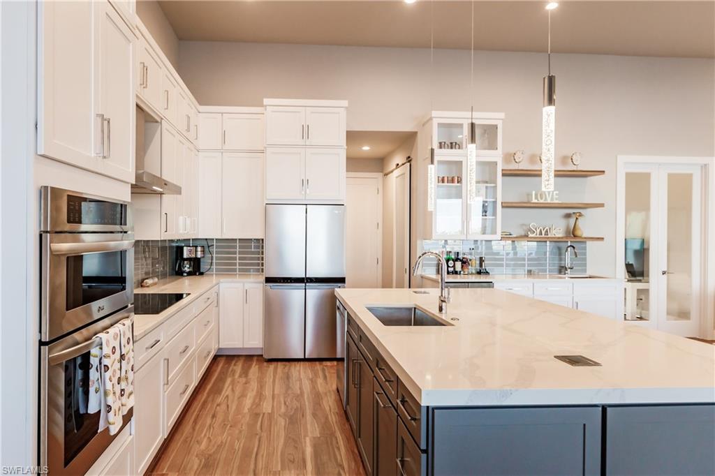 Kitchen with stainless steel appliances, open shelves, white cabinetry, tasteful backsplash, and recessed lighting