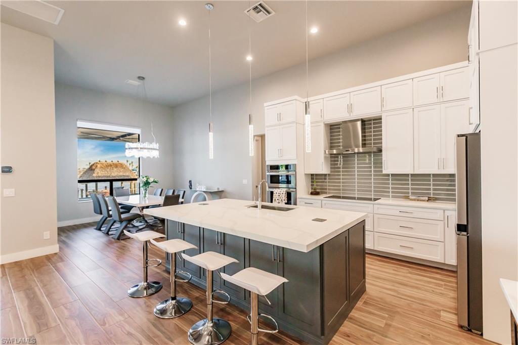 Kitchen featuring white cabinetry, light wood-type flooring, a kitchen bar, tasteful backsplash, and recessed lighting