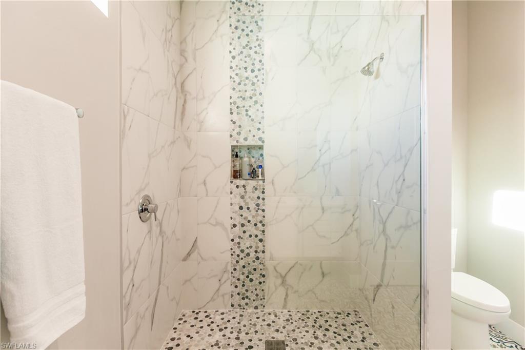 Full bath featuring a tile shower and toilet
