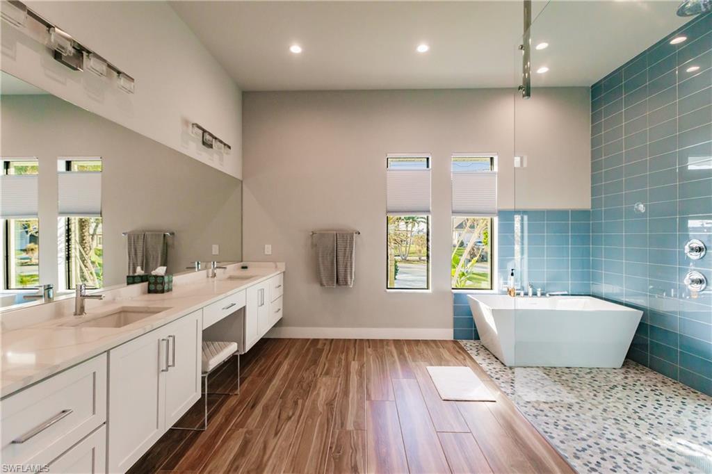 Full bathroom featuring plenty of natural light, a soaking tub, double vanity, recessed lighting, and tile walls