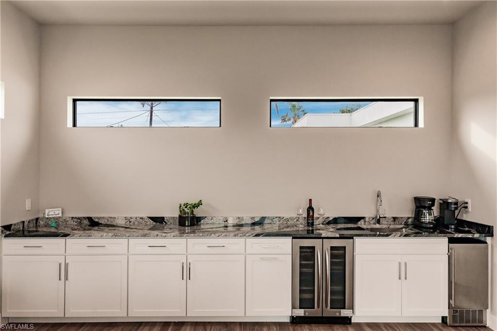 Indoor wet bar featuring beverage cooler and stainless steel refrigerator