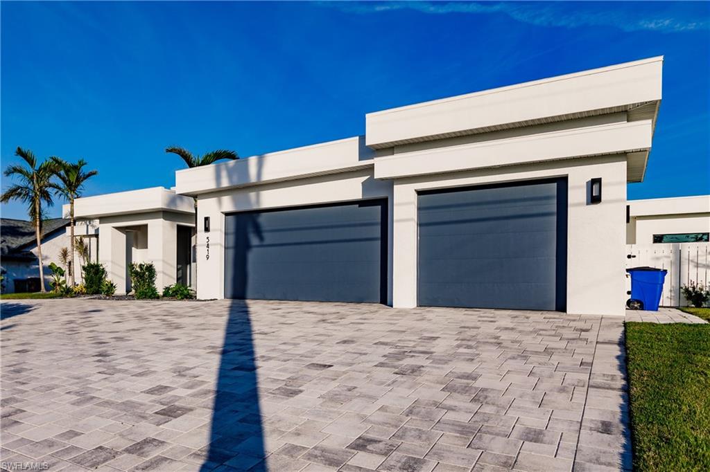 View of front of home featuring stucco siding, decorative driveway, and a garage