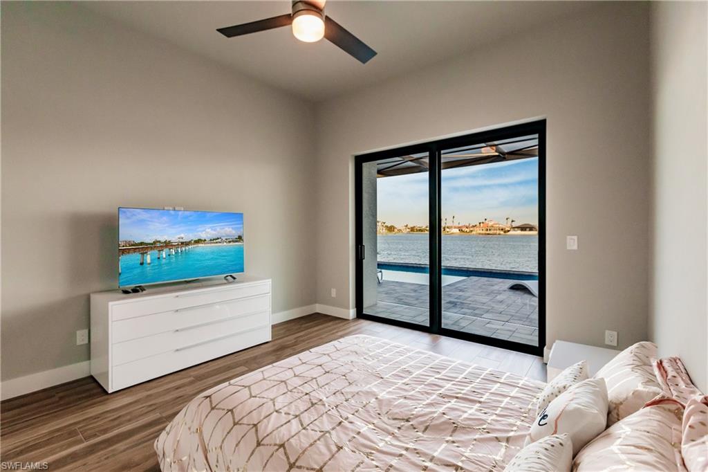 Bedroom featuring access to exterior, wood finished floors, and a ceiling fan
