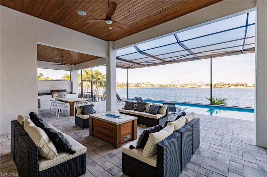 View of patio with an outdoor living space with a fire pit, exterior kitchen, ceiling fan, an outdoor pool, and a lanai