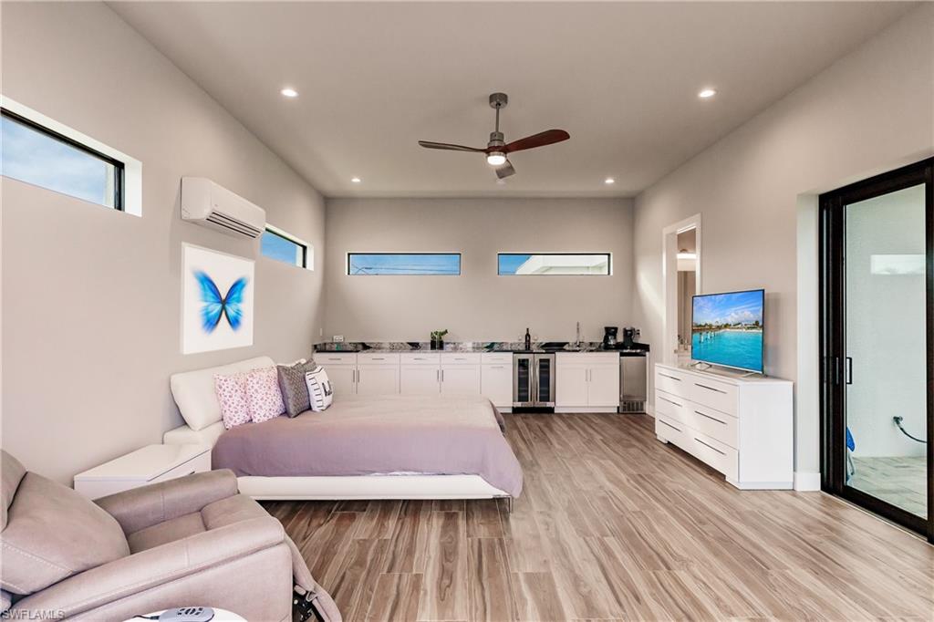 Bedroom with light wood-style floors, recessed lighting, wine cooler, a wall mounted AC, and a ceiling fan