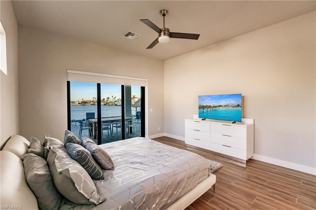 Bedroom featuring access to outside, wood finished floors, and a ceiling fan