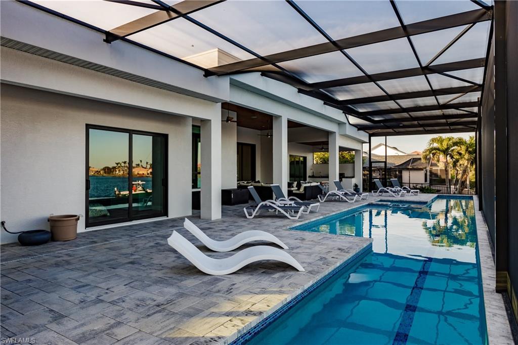 Outdoor pool with a patio area, glass enclosure, and a ceiling fan