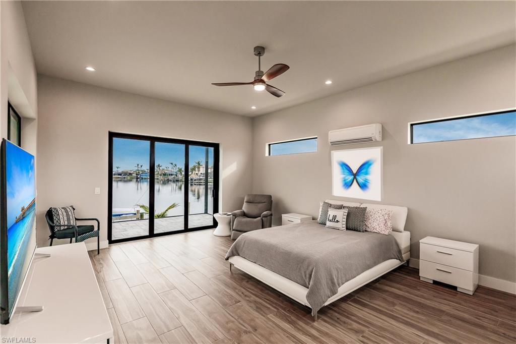 Bedroom with access to exterior, wood finished floors, recessed lighting, a water view, and a wall mounted air conditioner