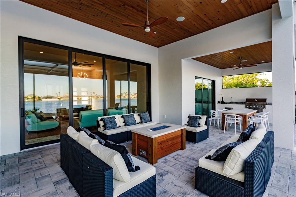 View of patio / terrace featuring a ceiling fan, an outdoor living space with a fire pit, and an outdoor kitchen