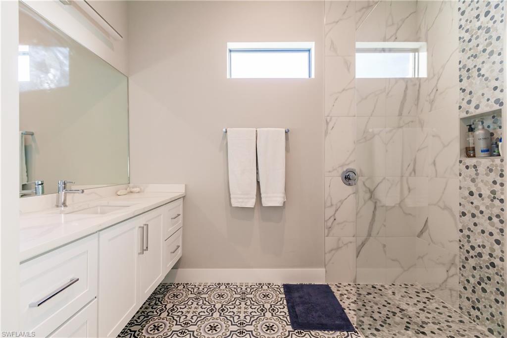 Bathroom with vanity and a marble finish shower