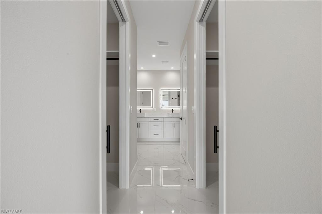 Corridor featuring recessed lighting and light marble finish floors