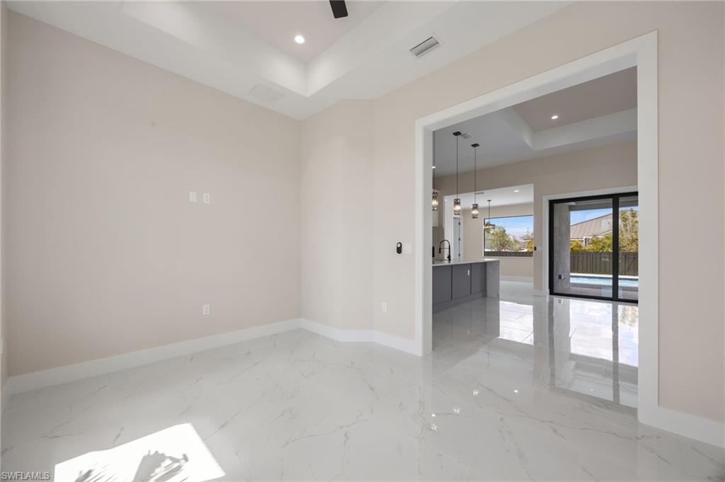 Unfurnished room with a raised ceiling, recessed lighting, and light marble finish floors