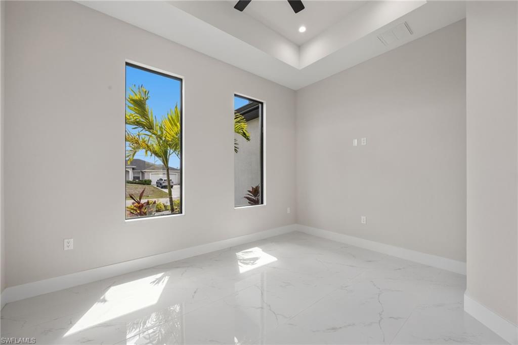 Spare room with a ceiling fan, a raised ceiling, recessed lighting, and light marble finish flooring
