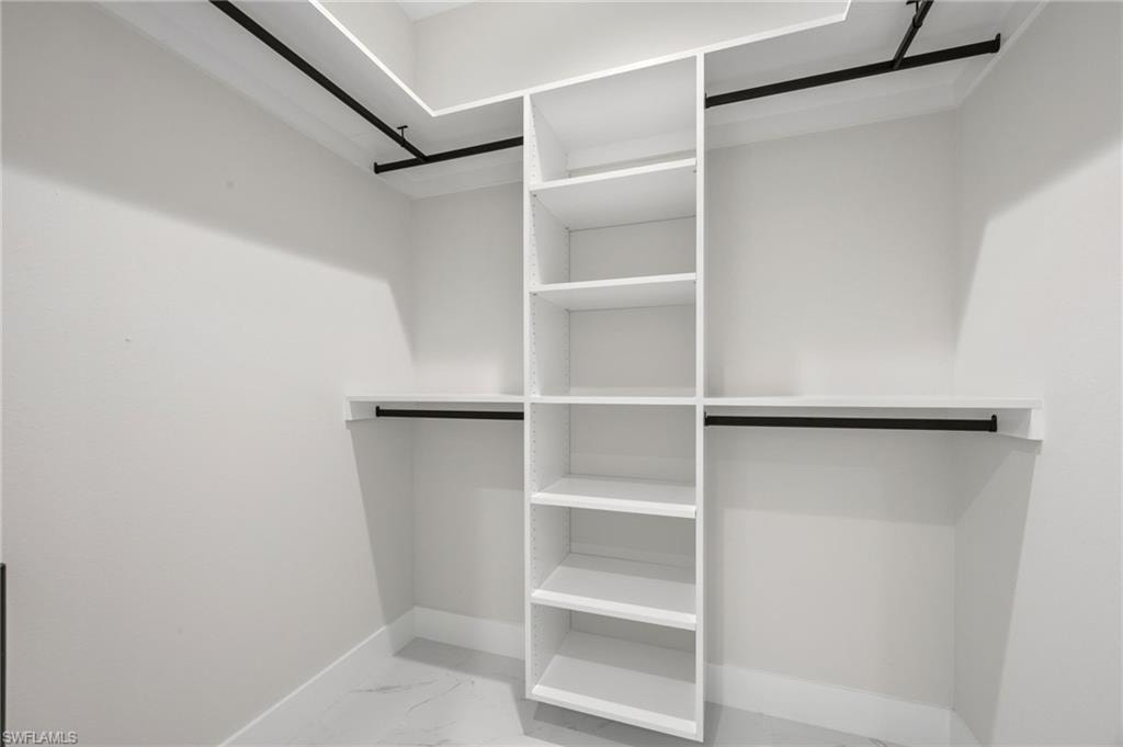 Walk in closet with light marble finish floors