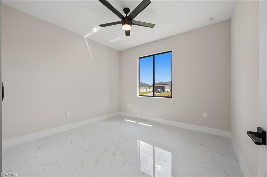 Empty room with light marble finish flooring and a ceiling fan