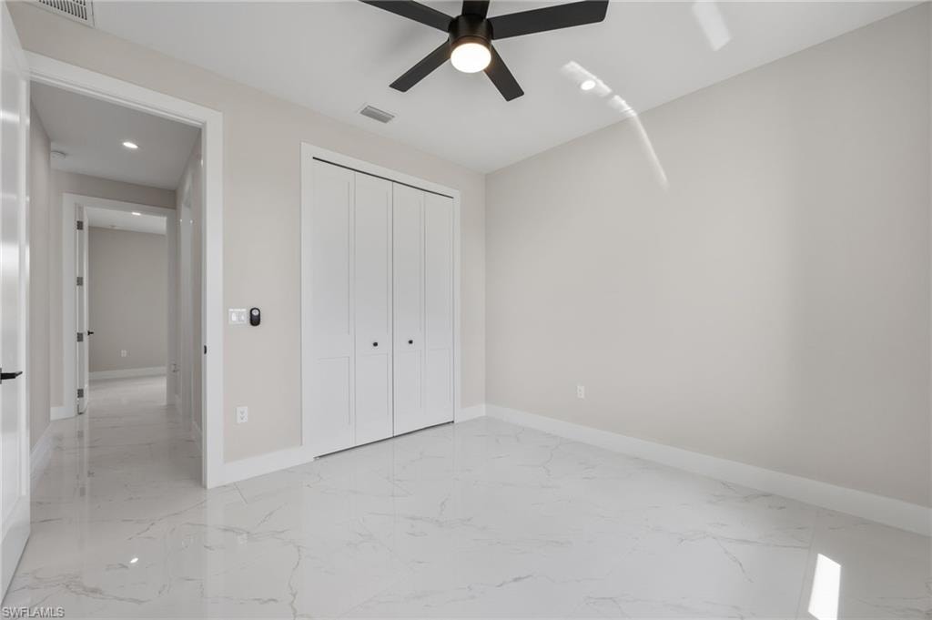 Unfurnished bedroom featuring light marble finish floors, recessed lighting, a closet, and ceiling fan