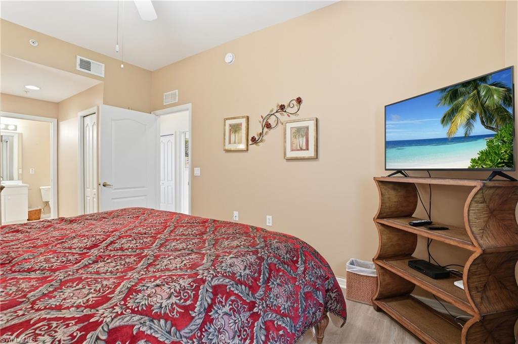 This bedroom features light-colored walls and flooring, with a ceiling fan providing air circulation