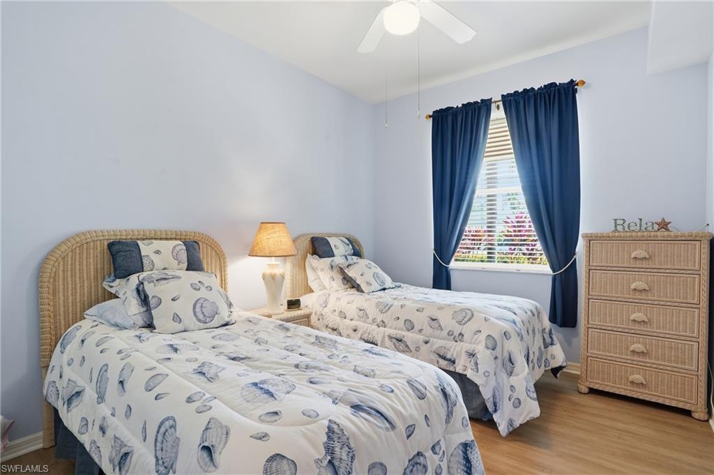 This room features light blue walls, two beds with wicker headboards, and a window with blue curtains