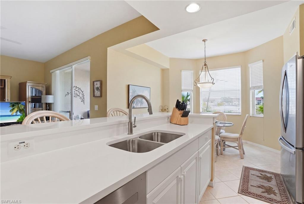 The kitchen features white countertops, a double sink with a gooseneck faucet, white cabinetry, and stainless steel appliances