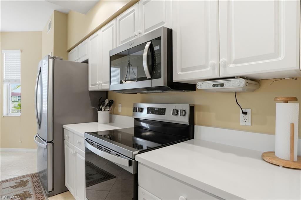 The kitchen features white cabinetry, stainless steel appliances, and white countertops