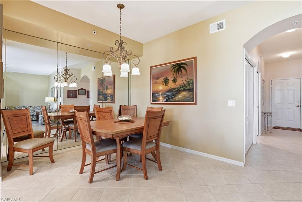 The dining area features tiled flooring, a decorative chandelier, and a wall-mounted mirror