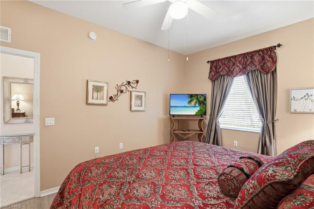 The bedroom features a ceiling fan, a window with blinds and drapes, and light-colored walls