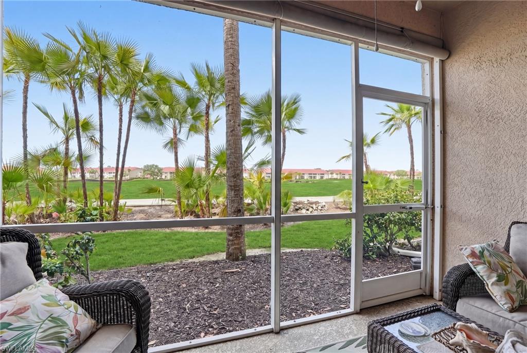 This property features a screened-in patio with a textured wall, offering views of a landscaped area with palm trees and a grassy expanse