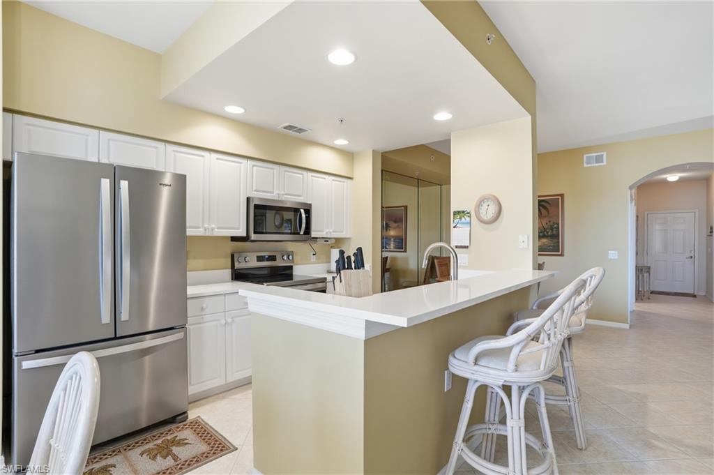 The kitchen features a stainless steel refrigerator, microwave, and range