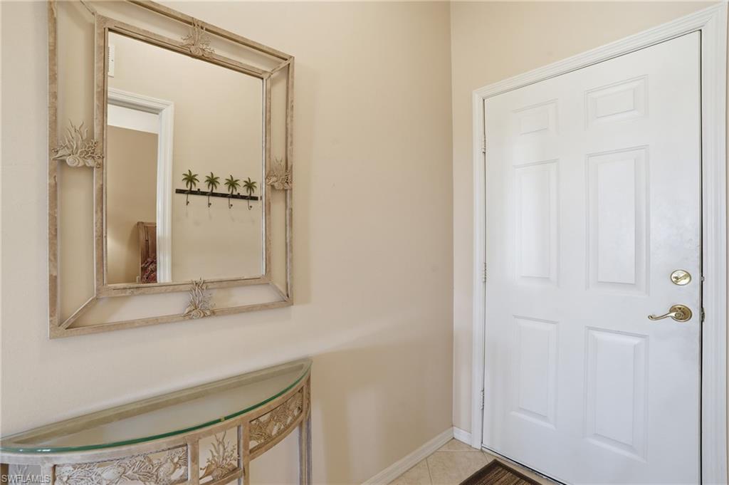 The entryway features a white paneled door with brass hardware, a decorative wall mirror with a light-colored frame, and a console table with a glass top