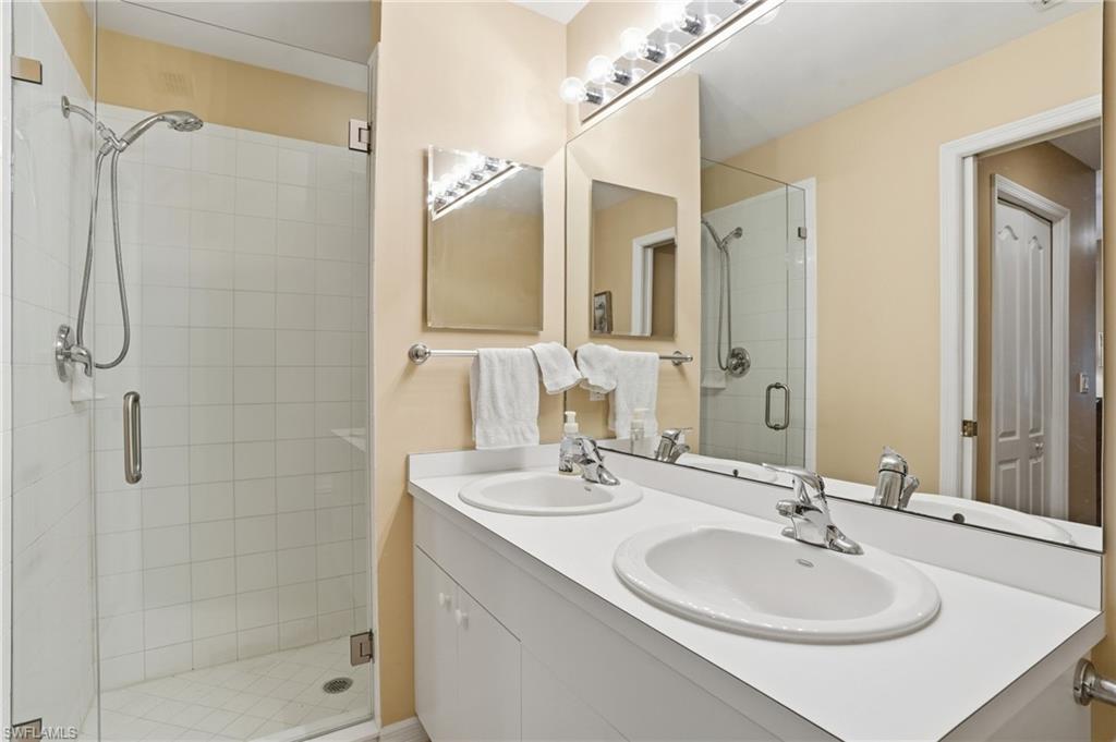 Bathroom featuring a double vanity with two sinks and a tiled shower with a glass enclosure