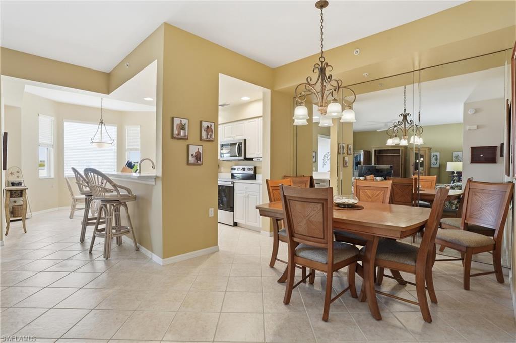 The dining area features a decorative chandelier, tile flooring, and a mirrored accent wall