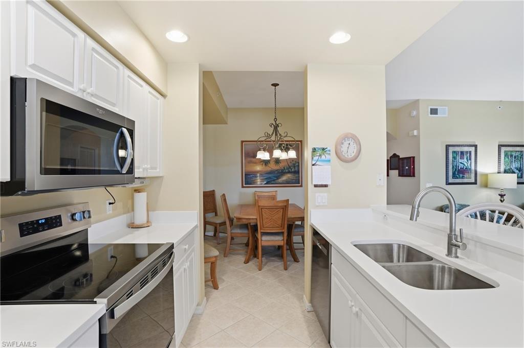 The kitchen features white cabinetry, stainless steel appliances including a microwave and range, and a double basin sink