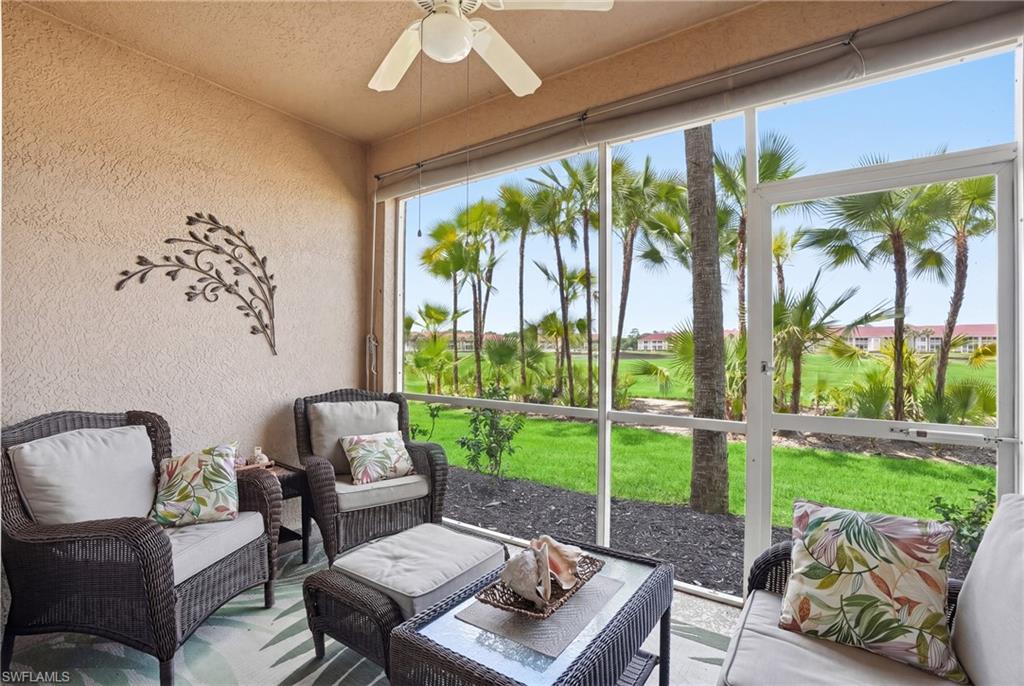 The screened patio features a ceiling fan, providing a comfortable outdoor living space with views of the expansive green lawn and mature palm trees