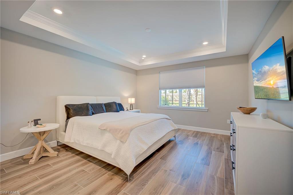 Master bedroom featuring elegant tray ceiling with recessed lighting