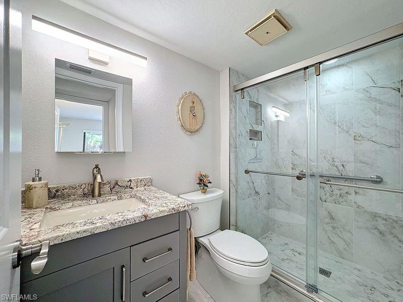Bathroom featuring vanity, an enclosed shower, and toilet