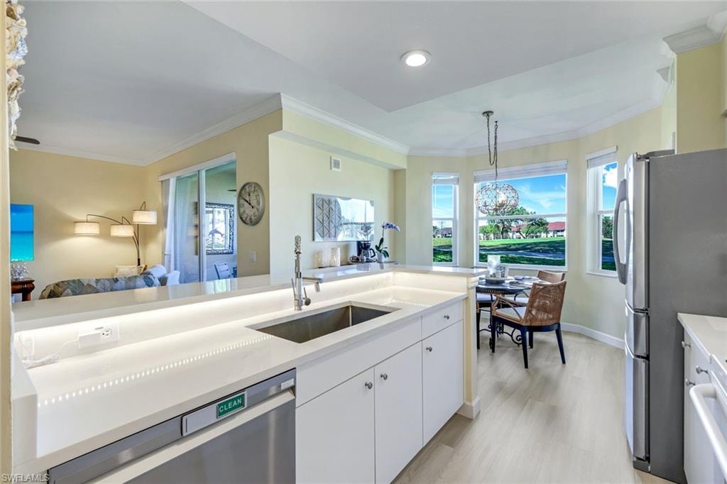 Kitchen featuring ornamental molding, a sink, stainless steel appliances, and open floor plan