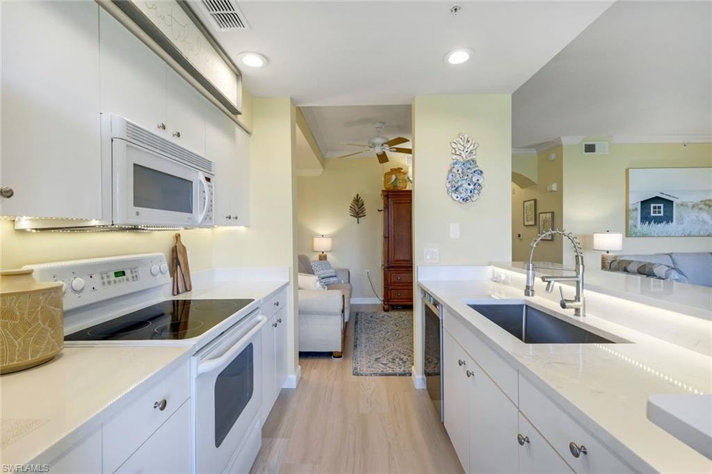 Kitchen with white appliances, open floor plan, visible vents, and a sink