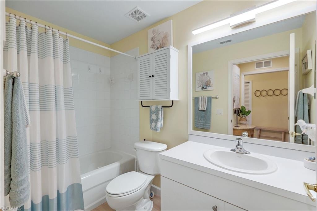Full bath with visible vents, toilet, shower / tub combo, and vanity