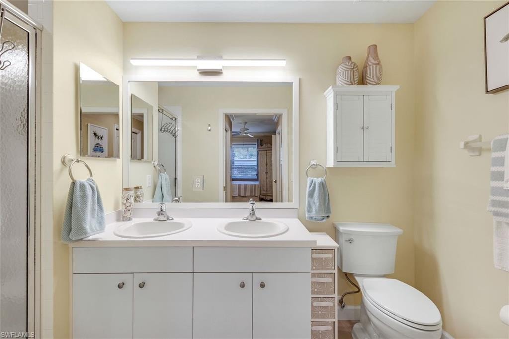 Bathroom featuring toilet, a sink, double vanity, and a shower stall