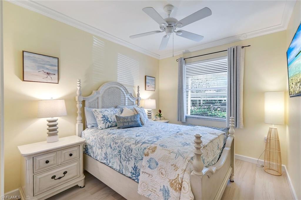 Bedroom with baseboards, ornamental molding, a ceiling fan, and light wood-type flooring