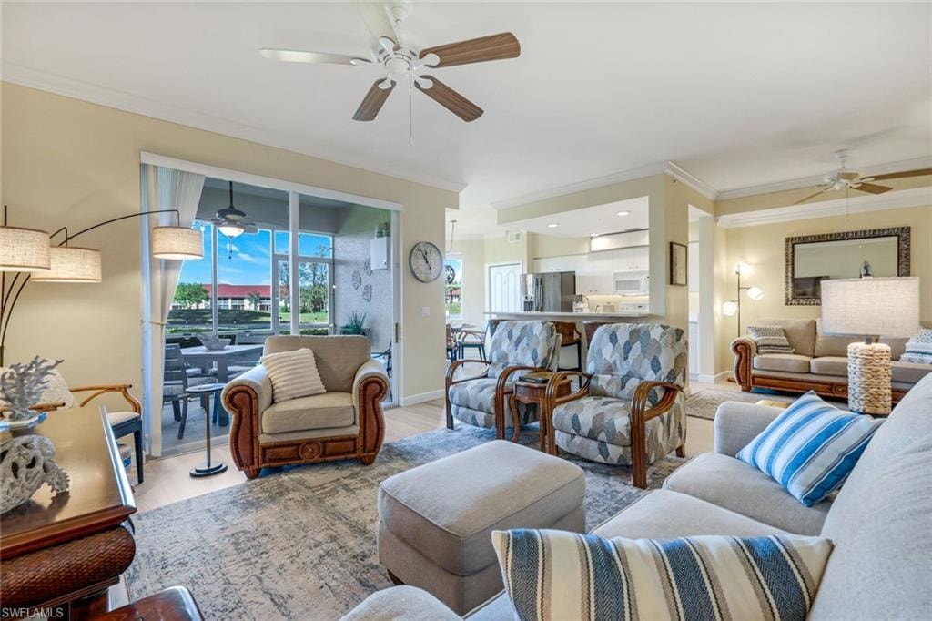 Living room with wood finished floors, crown molding, baseboards, and ceiling fan
