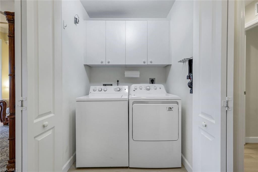 Laundry area featuring baseboards, cabinet space, light wood-type flooring, and washer and dryer