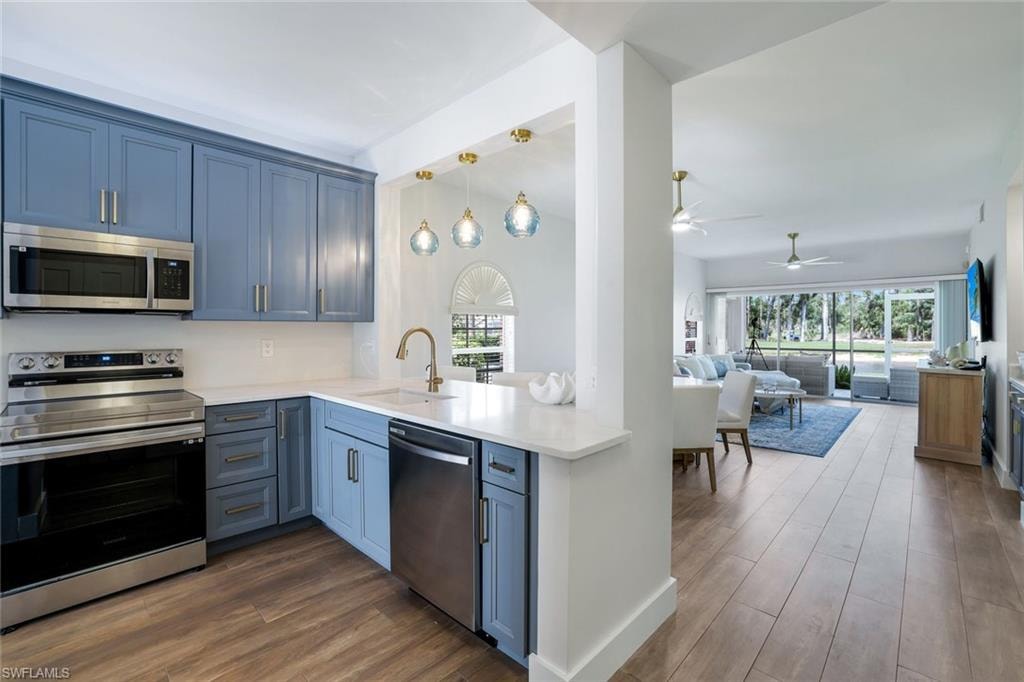 Kitchen with light countertops, stainless steel appliances, a sink, dark wood-style floors, and ceiling fan