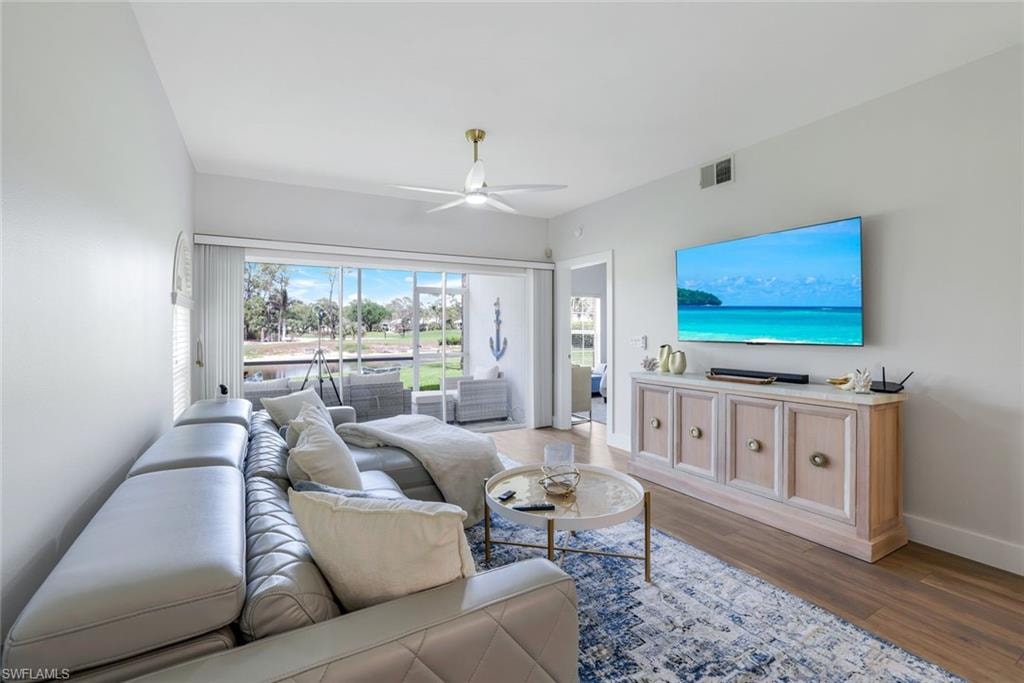 Living room with a ceiling fan, wood finished floors, baseboards, and visible vents