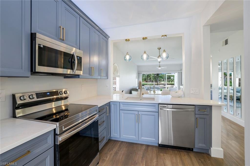 Kitchen featuring visible vents, dark wood-style floors, a sink, and appliances with stainless steel finishes