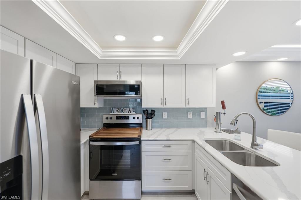 Modern kitchen featuring white cabinetry, stainless steel appliances, light-toned countertops, and a subway tile backsplash