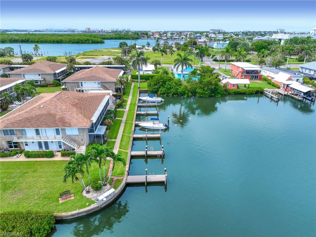 Waterfront multi-unit property featuring private boat slips, lush green lawns, and mature palm trees
