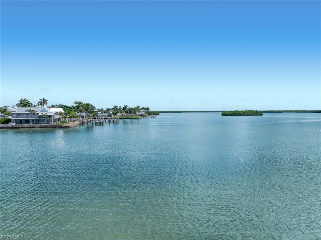 Expansive waterfront setting featuring clear blue water, a distant tree-lined island, and properties with private docks